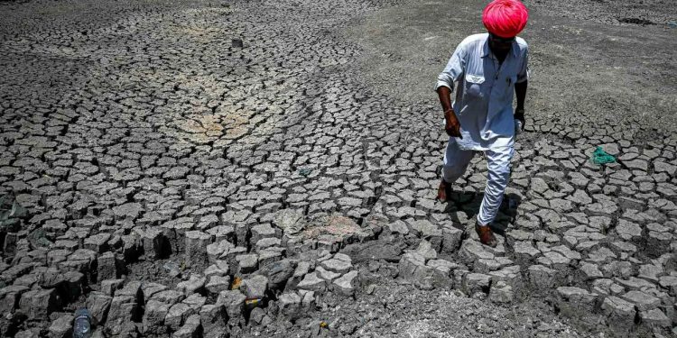 Homem caminha sobre o leito rachado de rio no estado de Rajasthan, Índia, em 11 de março. Crédito: Prakash Singh/AFP.