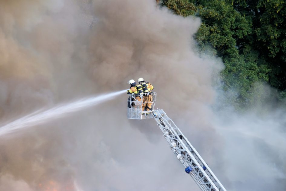 Dois bombeiros tentam parar um incêndio em uma floresta rodeada por fumaça