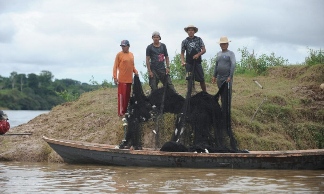 Ribeirinhos pescando em um barco na Amazônia, atividade de subsistência ameaçada pela contaminação de espécies de peixes por mercúrio.