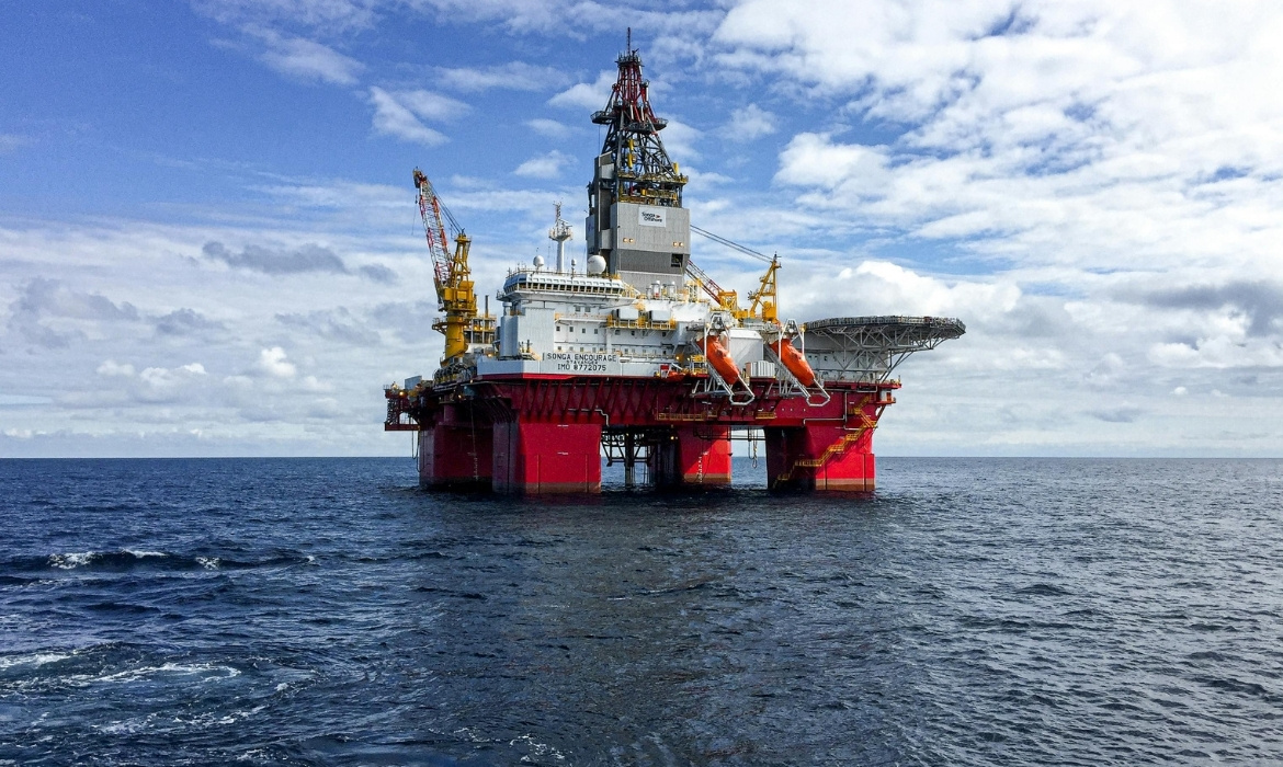 Imagem de uma sonda de perfuração marítima em operação no oceano, com estruturas metálicas e navios de apoio ao redor, representando o tipo de equipamento usado pela Petrobras na Margem Equatorial.