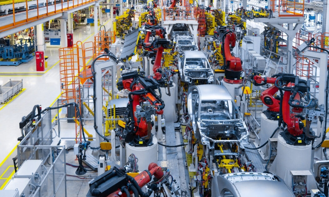 Linha de produção de veículos em fábrica automotiva, símbolo da transição para carros elétricos.
