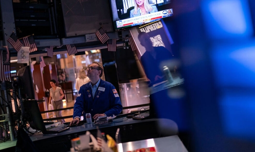 Painéis digitais da bolsa de valores em Wall Street simbolizando pressões sobre investimentos ESG e queda de pautas ambientais.