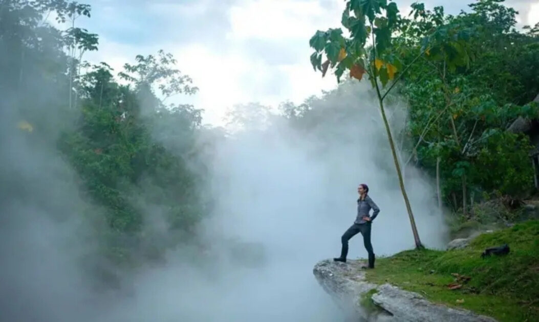 Pessoa observa o rio fervente da Amazônia envolto em nuvens de vapor quente.