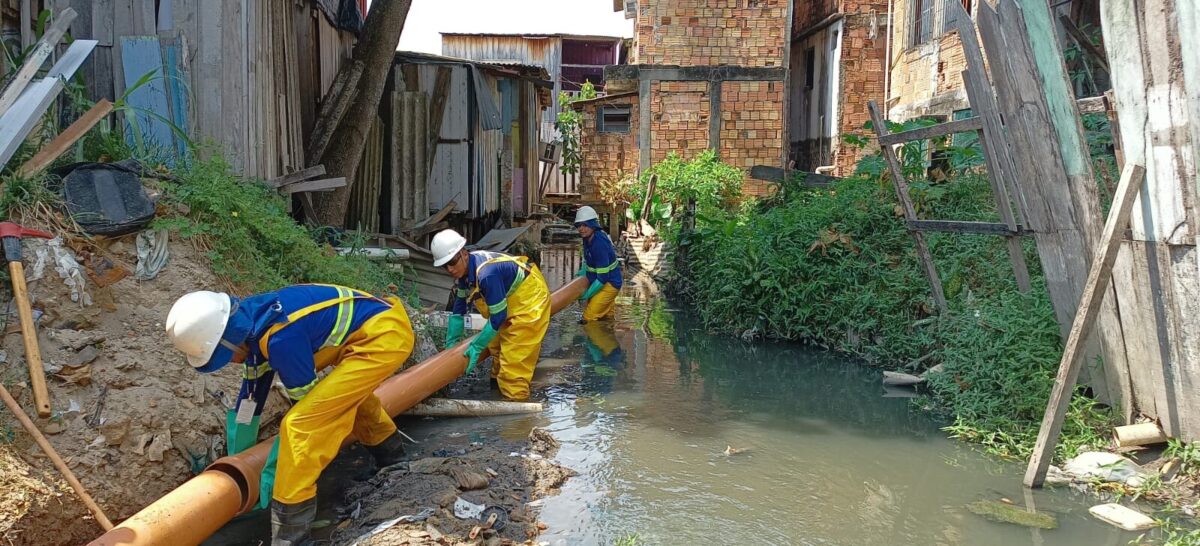 Trabalhadores de companhia de saneamento consertando canos em área urbana. 