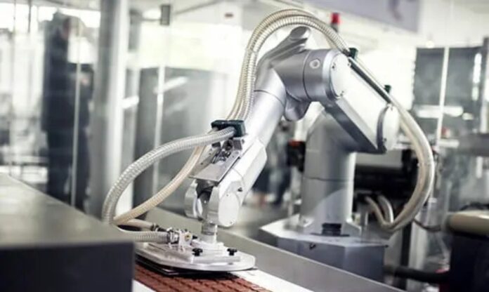 Braço robótico sendo usado em processo industrial, remetendo á longa experiência do IBBI com automação.