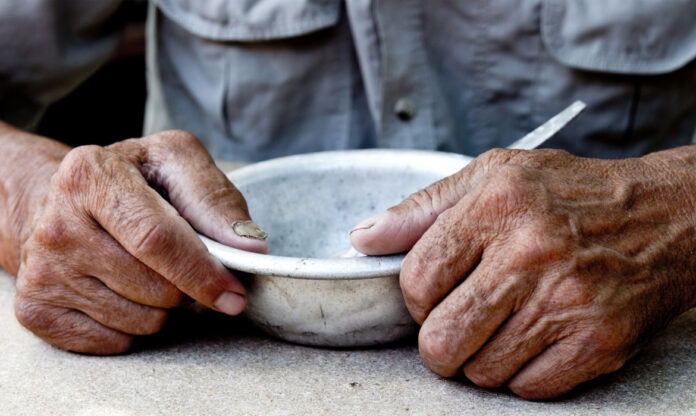 Idoso com prato vazio ilustra os impactos sociais do sistema alimentar global