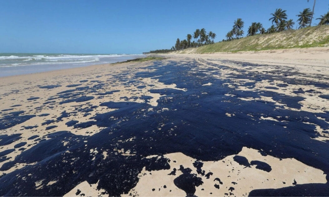 Superfície do mar coberta por manchas de óleo, indicando desafio ambiental onde soluções biomiméticas podem atuar.