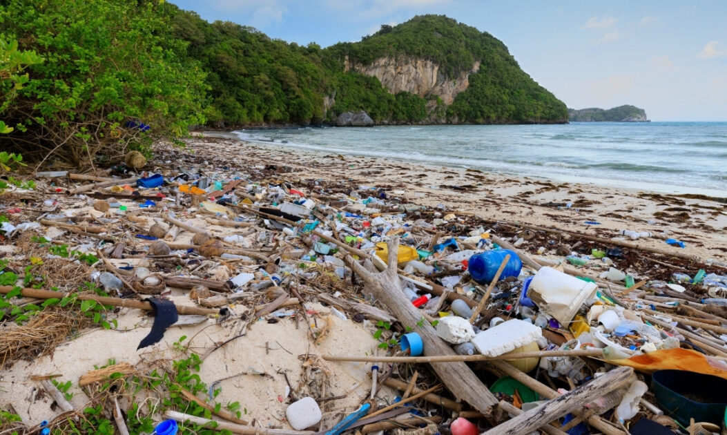 Praia coberta por lixo plástico, exemplo visível da tripla crise planetária nos oceanos.
