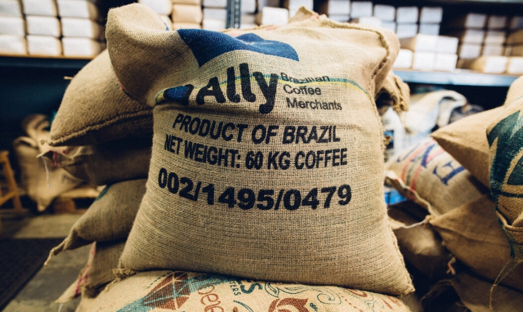 Saca de café cheia de grãos, representando a cadeia produtiva e os resíduos de folhas de café.