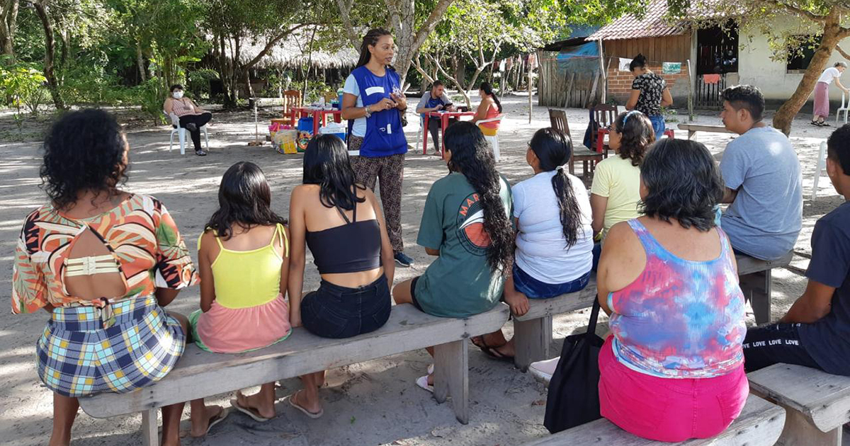 Pesquisadores conversam com ribeirinhos em círculo sobre os efeitos do mercúrio na saúde.