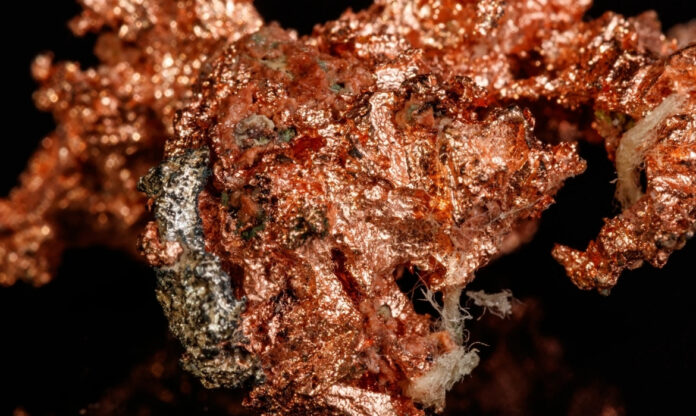 Macro de um fragmento metálico mostrando textura detalhada de cobre puro, usado como referência visual para pesquisas em catalisador de cobre para converter CO₂.