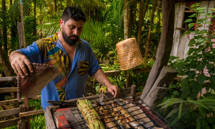 Chef prepara peixe na brasa ao estilo tradicional da gastronomia amazônica.