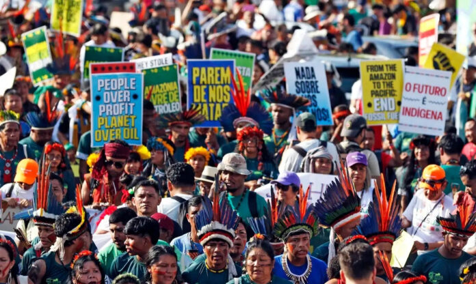 Indígenas marcham pelas ruas de Belém com faixas e cartazes durante a COP30.