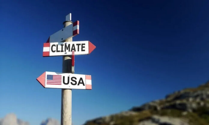 Placa com clima apontando para um lado e uma placa abaixo escrito EUA apontando em direção oposta, uma referência ao negacionismo climático do governo Trump.