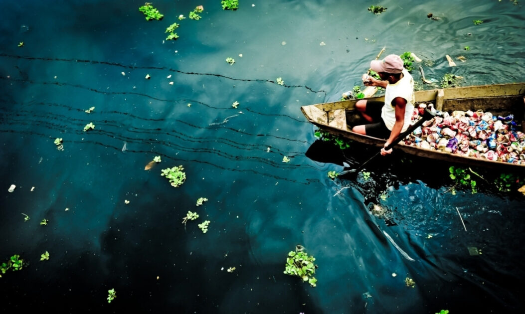 Homem em canoa recolhe resíduos plásticos de rio amazônico