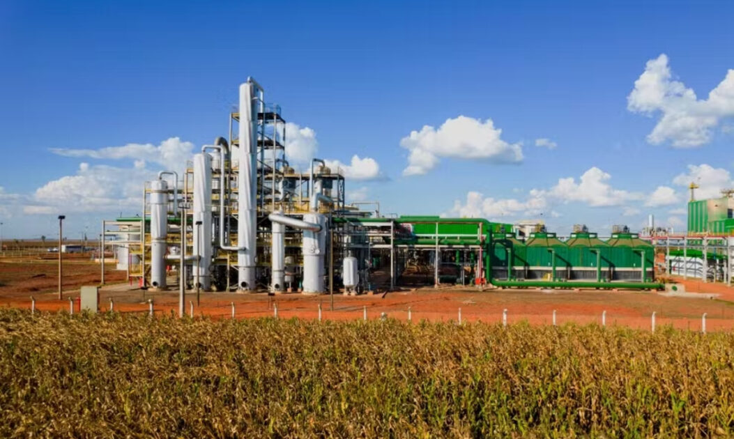 Vista externa de uma usina de etanol com silos e dutos, estrutura industrial associada à produção de bioenergia a partir da cana-de-açúcar.