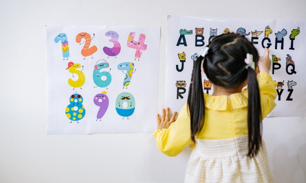 Criança em idade pré-escolar aprende letras e números em ambiente afetado pelo calor extremo.