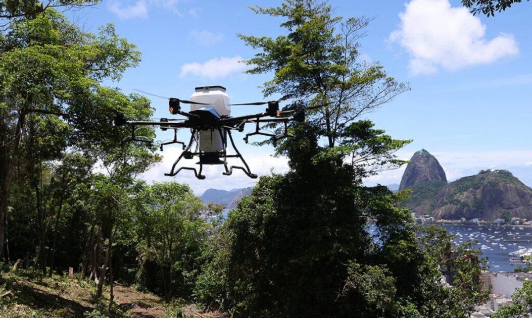 Drone sobrevoando área degradada e dispersando sementes em ação de reflorestamento aéreo