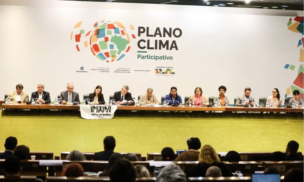 Reunião de autoridades com banner ao fundo indicando discussão sobre o Plano Clima.