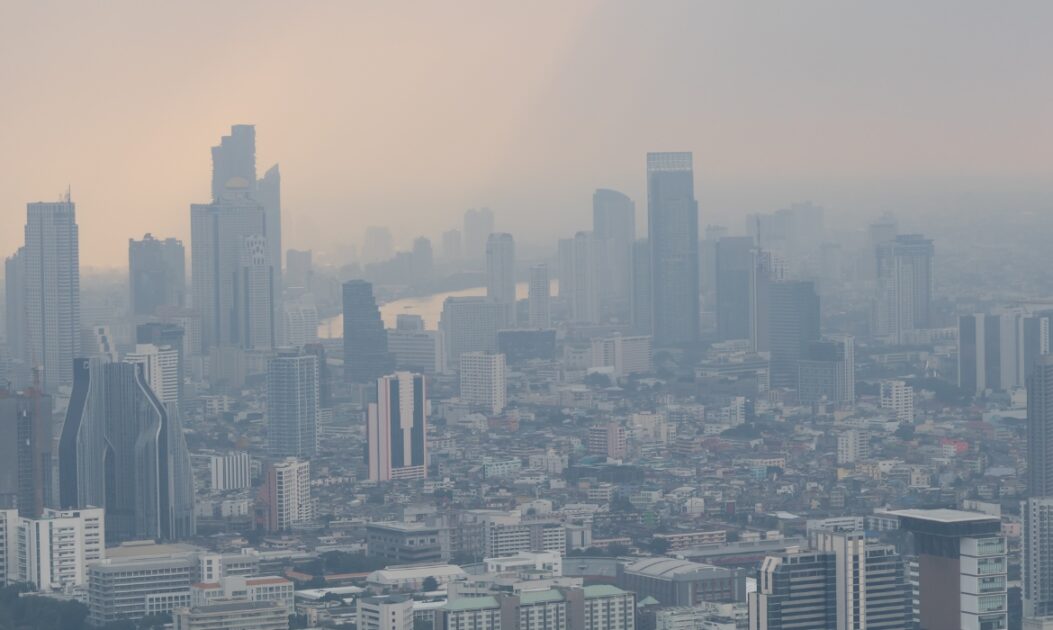 Vista urbana com prédios cobertos por névoa de fumaça causada pela poluição do ar.