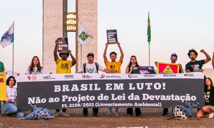 Manifestantes seguram faixas em protesto contra o PL da Devastação e em defesa do licenciamento ambiental no Brasil.