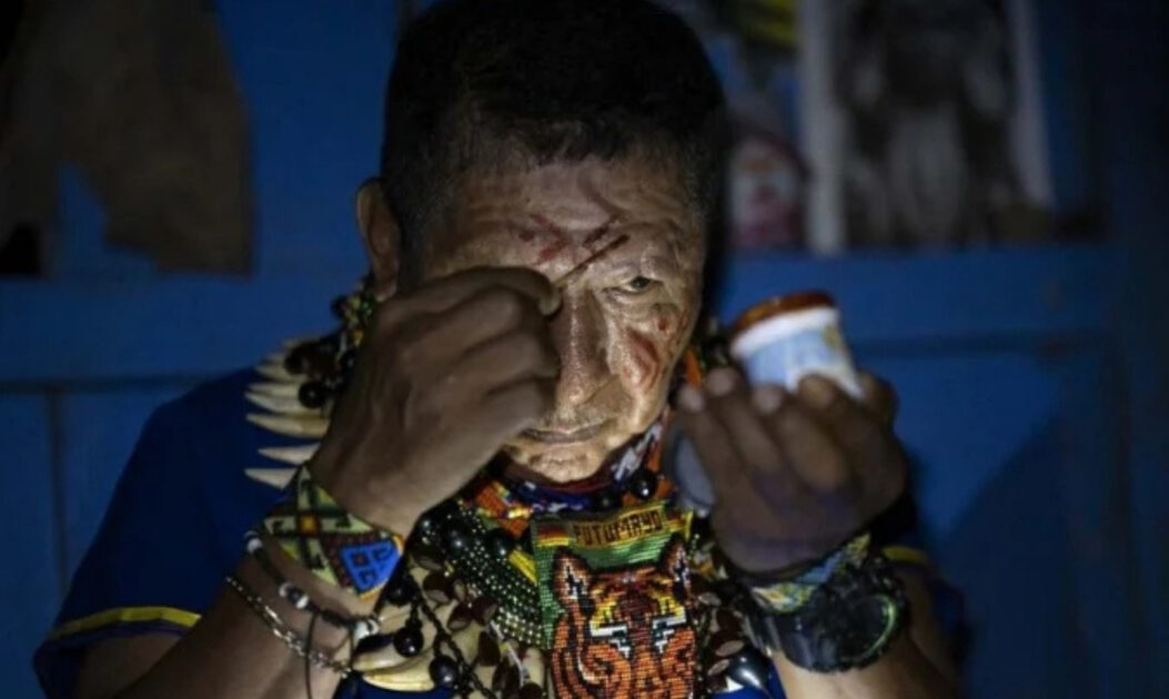 Isidro Lucitante, curador do povo Cofán, pinta o rosto com urucum antes de cerimônia de yagé (ayahuasca) na Amazônia equatoriana, prática ligada aos psicodélicos na Amazônia. Crédito: Pedro Pardo / AFP.