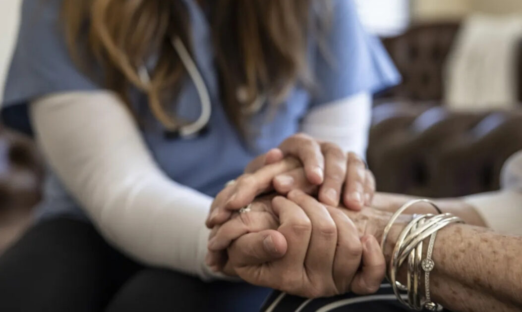 Médica segura a mão de paciente em ambiente hospitalar, simbolizando cuidados paliativos e pesquisas com psicodélicos no apoio à saúde mental.