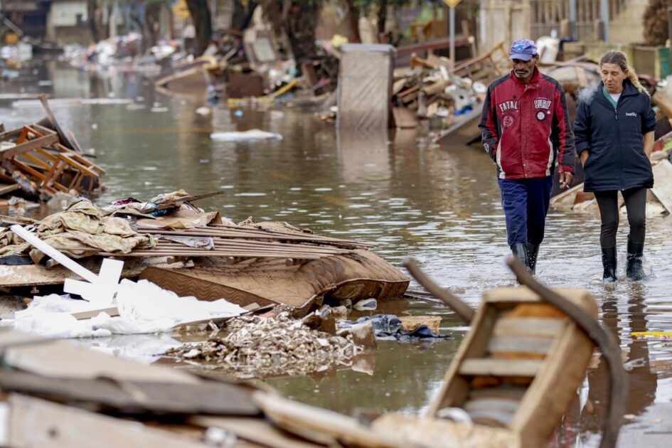 Moradores caminham em rua alagada pela enchente em Eldorado do Sul (RS), exemplo dos desafios da adaptação climática no Brasil diante de eventos extremos.