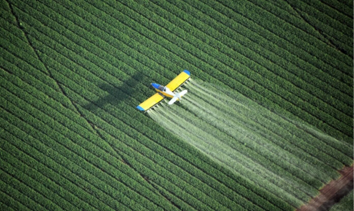 Avião agrícola pulveriza pesticidas sobre plantação, prática associada ao uso de agrotóxicos no Brasil na agricultura em larga escala.