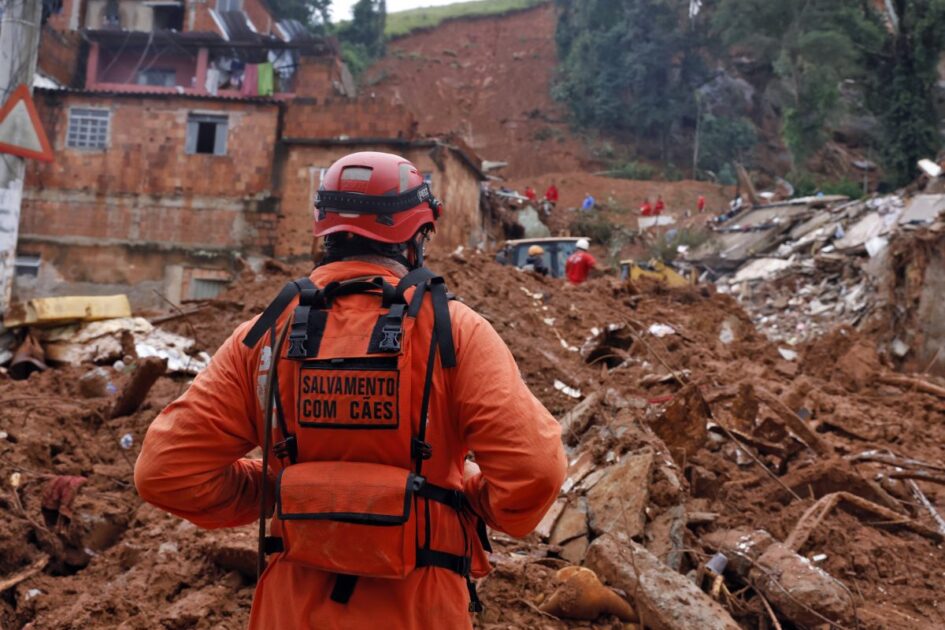 Bombeiro observa destroços após temporais em Minas Gerais, cenário que ilustra os desafios da adaptação climática no Brasil diante de desastres.