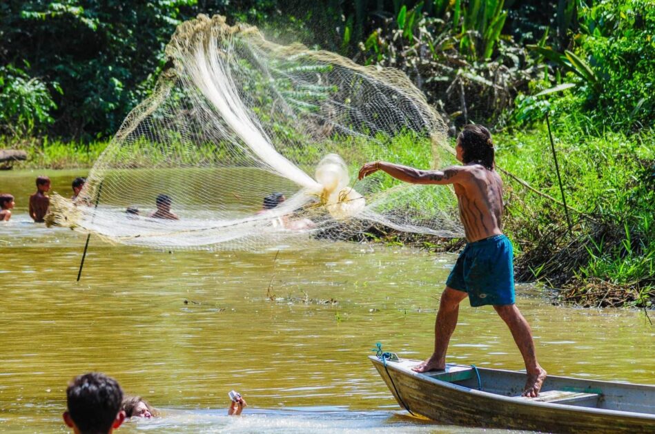 Indígenas pescando em rio amazônico, atividade ameaçada pela contaminação por mercúrio associada ao garimpo e aos desafios da mineração sustentável.