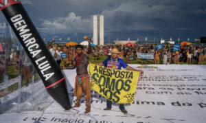 Manifestação indígena em Brasília durante o Acampamento Terra Livre com faixa e símbolo contra exploração, defendendo zonas livres de petróleo e gás