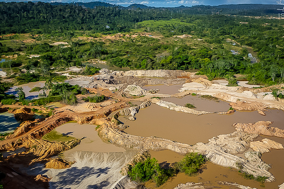 Imagem aérea de área de garimpo ilegal na Amazônia, mostrando desmatamento e impactos da mineração em terras indígenas.